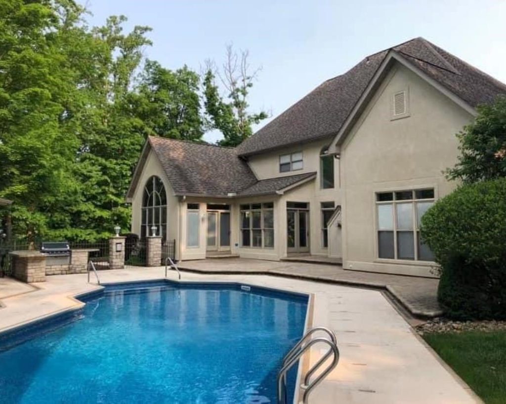 A home with a swimming pool and patio that requires pressure washing.