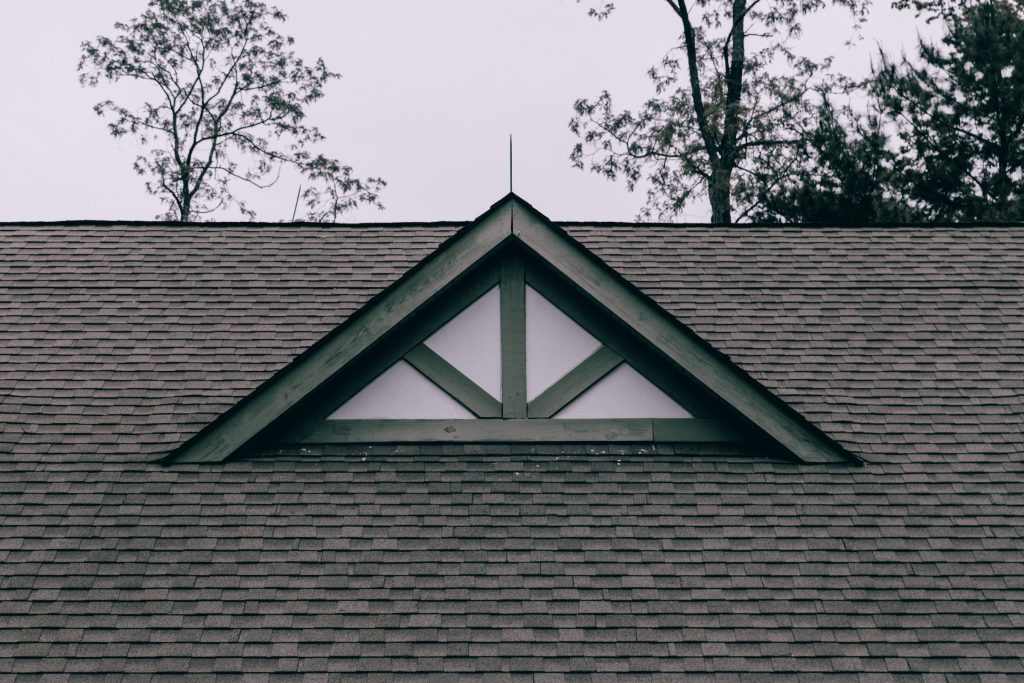 A roof with a triangular window on it that requires power washing.