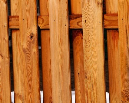 A close up of a wooden fence undergoing pressure washing.