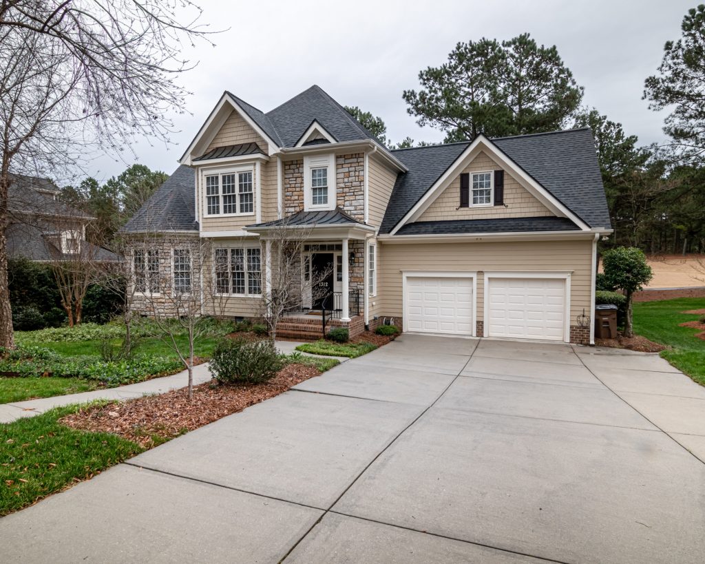 A home with two garages and a driveway in need of pressure washing.