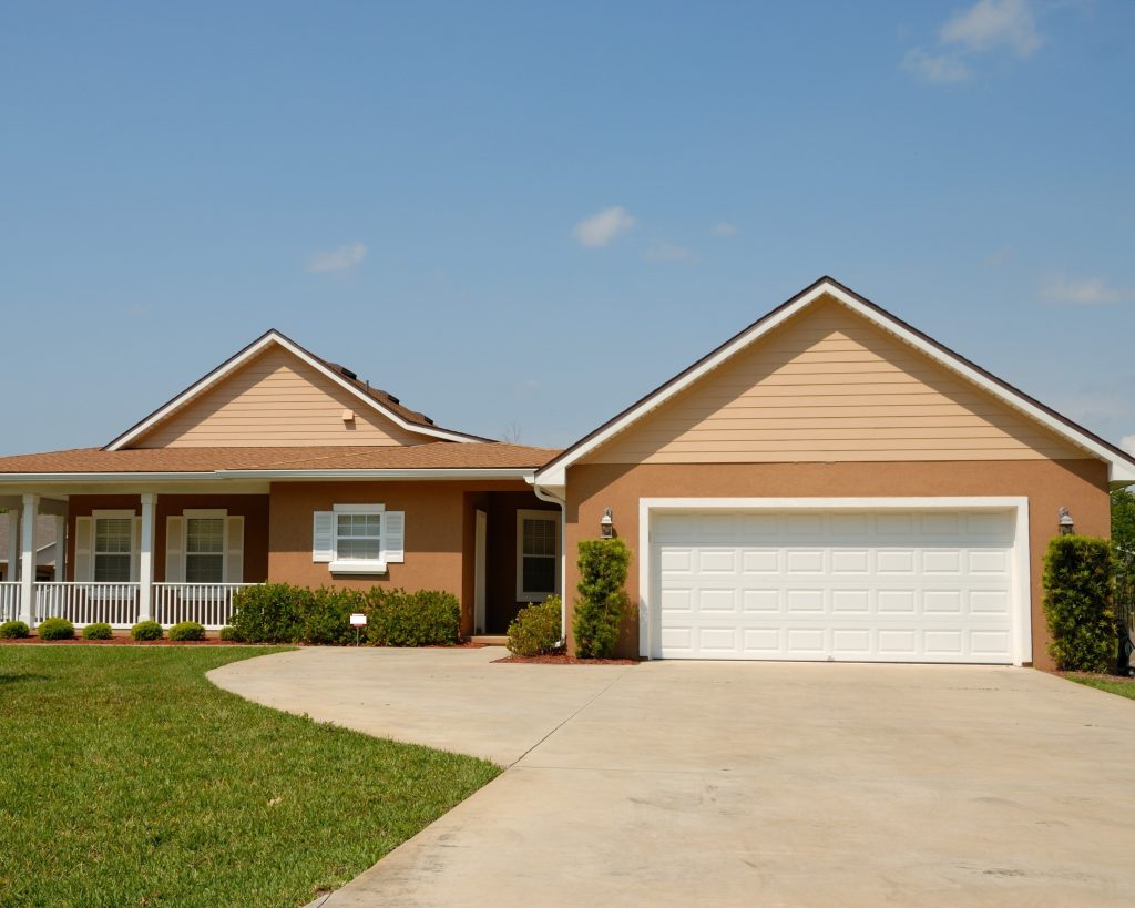 A tan house with white trim that could benefit from a power washing to restore its original vibrancy.