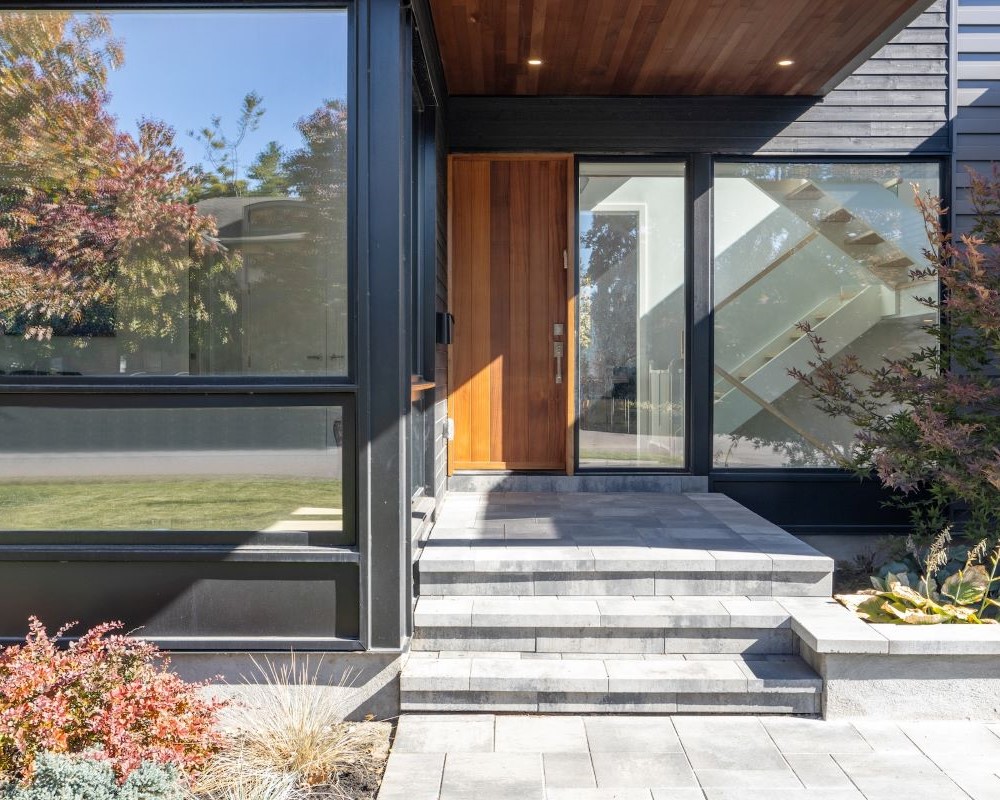 A pressure washed modern home with a glass front door.