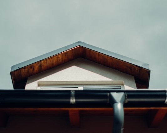The roof of a house with a chimney, cleaned through pressure washing.